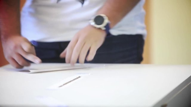 Video of a person casting a ballot at a polling station, during elections.