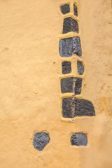 The yellow wall of the old house is decorated with stones