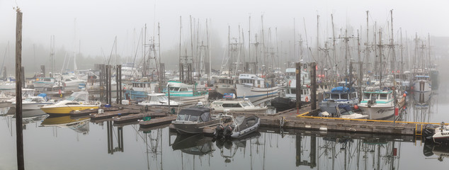 Ucluelet, Vancouver Island, BC, Canada - August 22, 2018: Fishing boats at a marina during a smoky and vibrant morning sunrise.