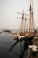 Obraz premium Port Hardy, Vancouver Island, BC, Canada - August 20, 2018: Wooden sailboat parked at a marina during a foggy summer day.