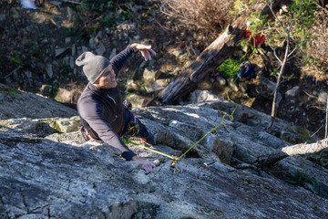Latin Male Rock climber climbing on the edge of the cliff during a sunny winter sunset. Taken in Area 44 near Squamish and Whistler, North of Vancouver, BC, Canada.