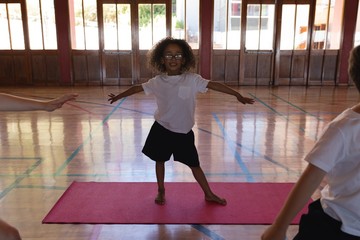 Schoolgirl doing yoga on a yoga mat in school © wavebreak3