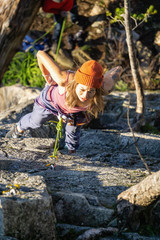 Squamish, BC, Canada - January 15, 2019: Female Rock climber climbing on the edge of the cliff during a sunny winter sunset.