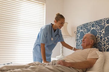 Female doctor interacting with senior man in bedroom