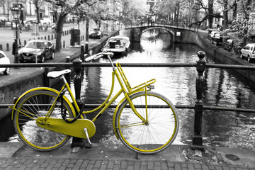 A picture of a lonely yellow bike on the bridge over the channel in Amsterdam. The background is...