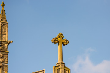 Fototapeta na wymiar stone cross on church roof with blue skies in background