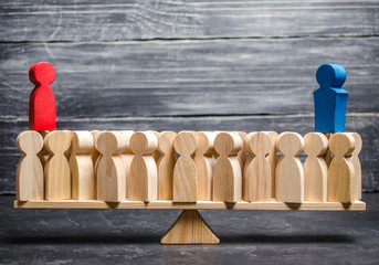 Red and blue figurines stand over a crowd of people. The rivalry of two people and the attraction of other people to his side. Political processes and games, debates. Elections. Conflict of interest.