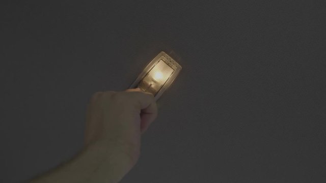 Male hand testing electric lamp of roof car pushing up and down the switch button