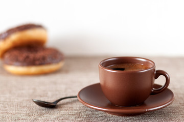 On the table is a cup of coffee with chocolate donuts