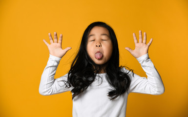 funny cute little asian girl shows the tongue