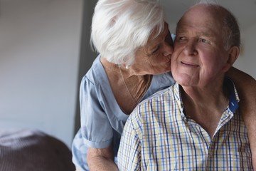 Senior woman kissing senior man at home