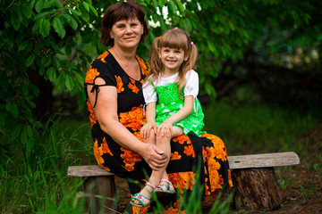 Fototapeta premium Happy grandmother and little granddaughter sitting in summer