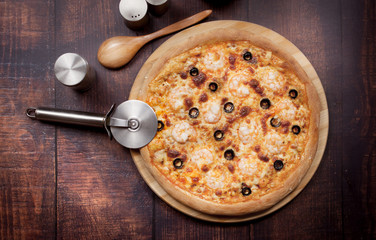 Pizza with shrimps and olives on a wooden table. Still life.
