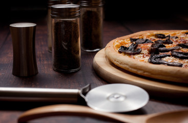 Pizza with mushrooms on a wooden table. Still life.