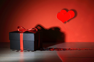 Czarne pudełko, prezent z czerwoną wstążką i sercem na deskach. - obrazy, fototapety, plakaty