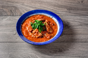 veal meat in tomato sauce with onion, garlic, chili peper on the wooden background. boiled meat and fresh tomato horizontal view