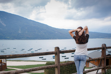 a girl looking towards a lake that has boats