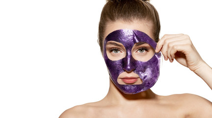 Studio portrait of charming model cleansing skin with face mask. Skincare beauty and wellness concept. Adorable young female standing on white background