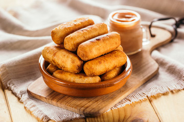 Cheese fingers, typical Venezuelan appetizer called tequeños accompanied with a pink sauce on a wooden board