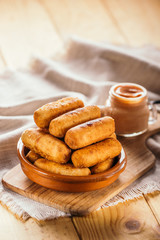 Fototapeta na wymiar Cheese fingers, typical Venezuelan appetizer called tequeños accompanied with a pink sauce on a wooden board