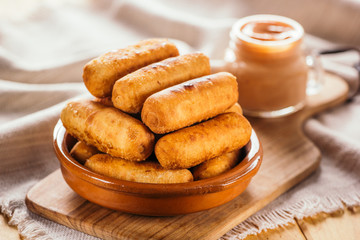 Cheese fingers, typical Venezuelan appetizer called tequeños accompanied with a pink sauce on a wooden board