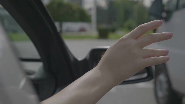 Carefree young woman waving her arm outside of moving car�window