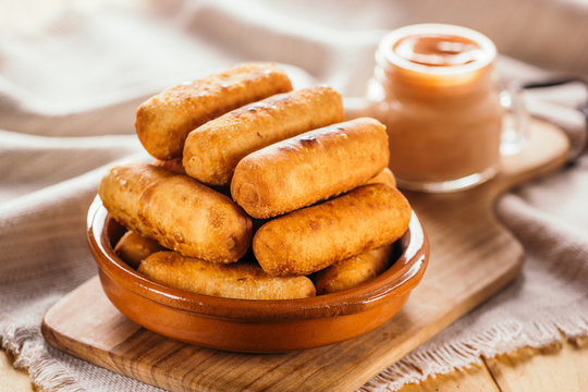 Cheese fingers, typical Venezuelan appetizer called tequeños accompanied with a pink sauce on a wooden board