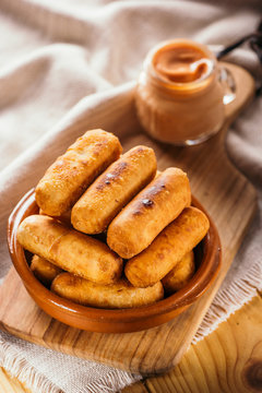Cheese fingers, typical Venezuelan appetizer called tequeños accompanied with a pink sauce on a wooden board