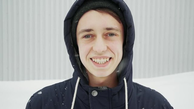 Close up portrait of a happy young man in the winter city with eye injury, hemorrhage in slow motion