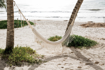 Romantic cozy hammock in the shadow of the palm on the tropical beach by the sea