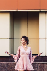 attractive young girl in a short pink dress posing near a beautiful building.