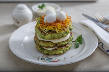 Zucchini fritters, vegetarian zucchini pancakes, served with quail eggs and carrots on top