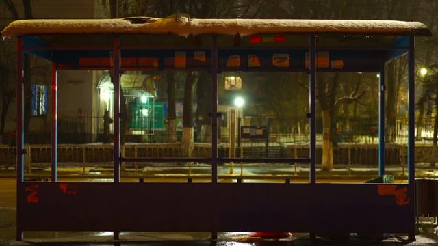 Empty bus stop covered with snow at night.