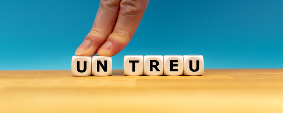 Zwei Finger schieben die W&uuml;rfel mit den Buchstaben U und N zur Seite und ver&auml;ndern das aus W&uuml;rfeln geformte Wort "untreu" in "treu".