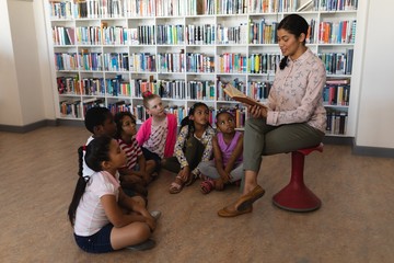 Female teacher reading a story to schoolkids 