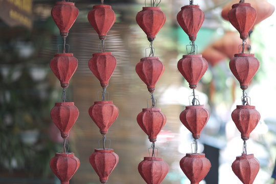 Rows of old electric garlands with lamps under the cloth shades on the wire frame ceiling. Vietnam