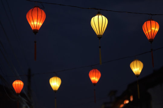 Multi-colored lights hanging on the wires of the decorative street illumination of the night city. Vietnam