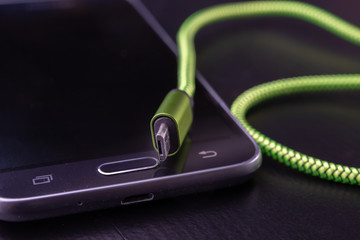 A usb cable for data transfer and phone charging. Telephone and accessories on the table.