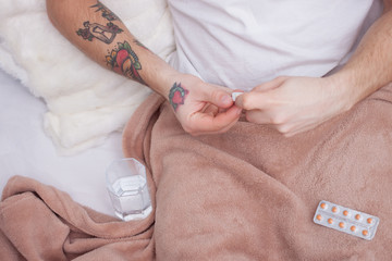 Young man with pill and glass of water at home