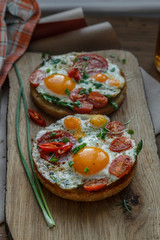 Toasts with eggs and tomatoes on cutting board