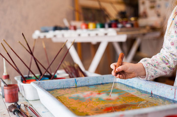 Little girl draws on Ebru technique.  Hand close up  