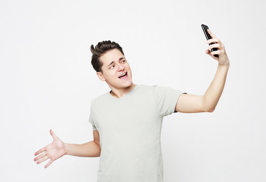 lifestyle and people concept: Photo of handsome man smiling on camera taking selfie isolated over white background 