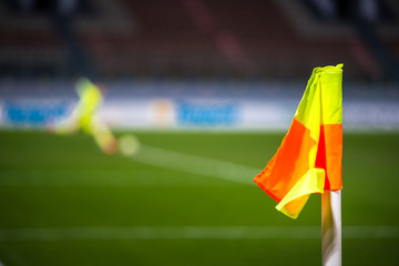 Football concept photo. Corner flag at the stadium, soccer goalkeeper in background