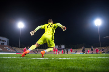 Goalkeeper catching the ball, night football match, stadium, spotlight