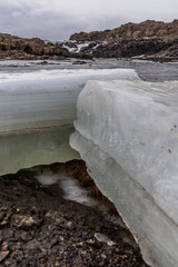 Eisblock vor einem Wasserfall im Winter in Island