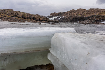 Eisblock vor einem Wasserfall im Winter in Island