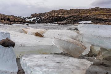 Eisblock vor einem Wasserfall im Winter in Island