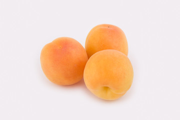 Three apricots lie side by side isolated on white background. Close-up photo
