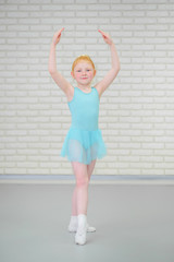 Cute little ballerina in blue dress dancing at ballet class.