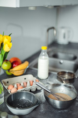 Up down shot of pancakes in the kitchen, home with flowers, eggs, fruits on the table.